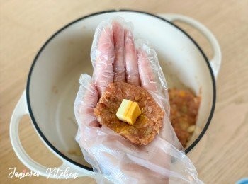 step8: 取出一團肉碎並按平，中間放入芝士粒，再用雙手搓成肉丸。可以雙手來回撻肉丸幾次，令肉丸口感更好。