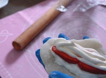 step8: 把粉團壓扁，包入忌廉和兩粒士多啤梨，揉成海獅形狀，然後用朱古力漿畫上裝飾，再撲上手粉，放入雪櫃半小時後即可食用。