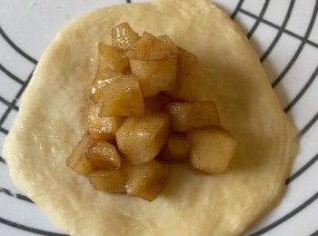 step6: 將麵糰分割成12份(約52克)，蓋上保鮮紙，靜置10分鐘；取1份麵糰，排氣，滾圓，壓平，加入1.5湯匙餡料，收口壓實。