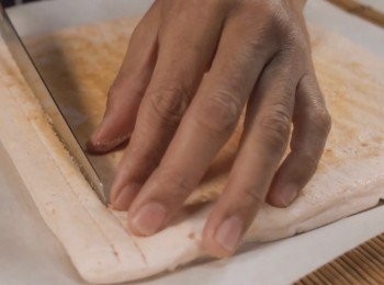 step7: 焗完的蛋糕放涼後，
用一張呎吋比蛋糕模大一點的牛油紙覆蓋上去，
然後翻面，把蛋糕脫模。
把蛋糕本身黏附著牛油紙斯掉。

*在蛋糕表面用刀先切一點點 會比較容易卷起來。