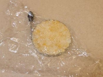 step4: 將圓形模放在工作枱上，再鋪一層保鮮紙，白飯放入中間，隔住保鮮紙用手輕輕壓成飯糰