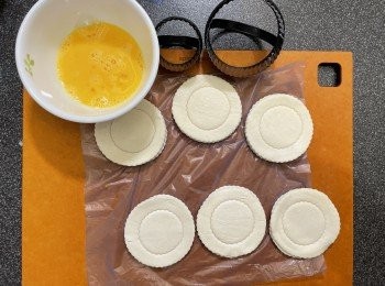 step5: 另外用一個細尺碼圓形模具輕壓酥皮，不要太用力壓穿酥皮底，酥皮盒掃上蛋液，焗盤鋪上牛油紙，放上酥皮盒，爐溫設200度，焗製時間設18分鐘（需目測決定實際時間）