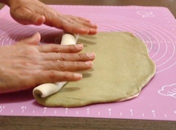 step7: 在牛奶麵皮表面灑上一層水分，再鋪上抹茶麵皮，用手輕輕壓實，再用捍麵掍把兩塊麵皮平均壓平，然後在麵皮表面再灑上一層水分，慢慢把麵皮捲起，把麵團尾部壓平收口，再滾成長條狀。