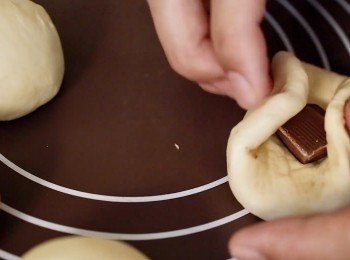 step3: 把麵團分成8份。加入巧克力，揉圓。
放在烤紙上發酵20分鐘。