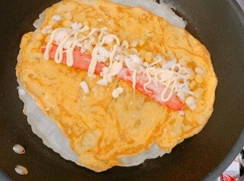 step4: 在餅皮上鋪上雞蛋、蟹柳、粟米粒、芝士碎及沙律醬，把蛋餅捲起。