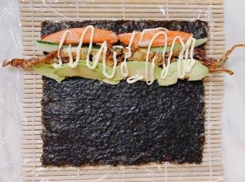 step5: 先把飯鋪平在紫菜上，反轉飯該面，在紫菜上鋪上牛油果片、青瓜、蟹柳、軟殼蟹，並吱上沙津醬卷起