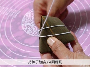 step7: 把上邊兩端葉子向下折蓋着頂部，成為密封的三角形，把棉繩的一邊固定，另一邊把粽子纏繞3-4圈綁緊。
