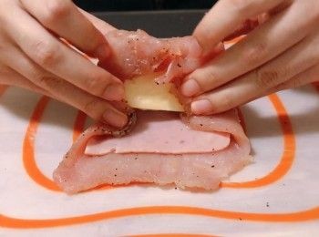 step4: 把豬扒放在砧板上，鋪上火腿和芝士，然後把豬扒捲起，包上保鮮紙把豬扒卷定型，放入雪櫃冷藏30分鐘備用。