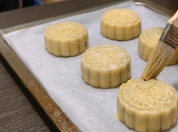 step14: 5) 把月餅取出，在月餅的外圍和頂部掃上一層薄薄的蛋液可用1-2茶匙水稀釋避免過於稠杰，放置10-12分鐘把蛋液吹乾和內餡降溫，防上象腳，再掃上一層蛋液，放入焗爐在中層用上下火220°C焗5分鐘，把餅皮焗熟。