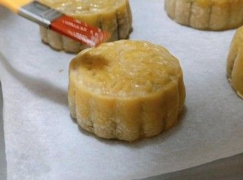 step15: 6) 把月餅取出，放置10-12分鐘把內餡降溫，防上象腳，然後在月餅的頂部掃上一層薄薄的蜜糖(蜜糖用適量的水稀釋，可加上1滴老抽使色澤更深)，放入焗爐在上層只用上火220°C焗3分鐘，把月餅上色。