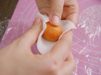 step8: 把麵團的底和面鋪上保鮮紙，用膠片壓成圓形，包入<span class="group_2">南瓜餡</span>，收口並搓成圓形。