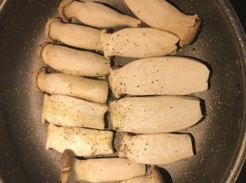 step3: 平底鍋燒熱下少許優質橄欖油，排入杏鮑菇片，撒少許鹽和黑胡椒粉，用中火煎；