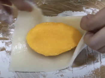 step6: 把芒果肉放在糯米皮上，平的一面朝上，包起來，剪掉前後多餘的糯米皮，沾適量手粉