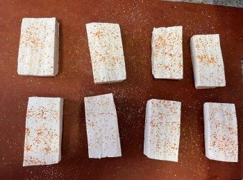 step4: 充分抹乾豆腐的水份、切塊、放在砧板上，然後在表面均勻灑上鹽和七味粉，完成後均勻地灑上一些粟粉裹面，反轉重覆灑上調味料和粟粉。