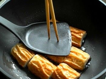 step3: 熱鍋加油，放入竹輪並用鍋鏟稍微壓一下，將竹輪表面煎至微微焦黃。