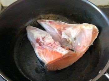 step3: 燒熱鑊，下油加熱，皮要向下地把三文魚頭煎香，然後反轉再煎另一邊，連同生薑一同煎香。