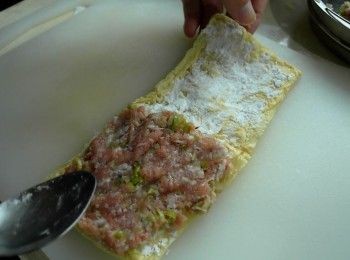 step2: 生豆包攤開，撒上薄博一層太白粉後將適量絞肉鋪在豆包上，再將豆包對折包好。