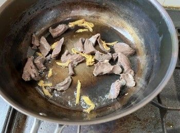 step4: 燒熱鍋、下麻油，待油燒熱後加入薑絲拌炒出香味，然後加入豬心片、米酒炒香。