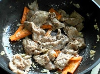 step3: 熱鍋加油，放入豬肉片煎至全熟。放入蒜末、胡蘿蔔、黑胡椒粉拌炒均勻。