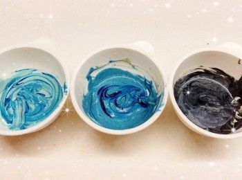step12: 然後將白朱古力溶液分成2部份（75 g＋325 g）2. 再將白朱古力溶液（75 g）分成3等份，各加入適量的藍色食用色素／蝶豆花粉和竹炭粉（需過篩），調成不同程度深淺的藍色和黑灰色（如想呈現出大理石般的紋路，只需輕輕的切拌幾下即可，不需拌勻）