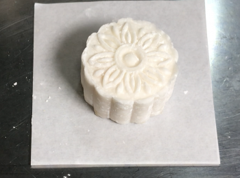 step5: 月餅團滾圓，表面沾粟粉，50克月餅模沾少許粟粉，把月餅模放在月餅團上用力壓幾下