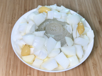 step3: 將一個碗倒放在盤上，在碗四周放蘋果和洋蔥，最後加上蒜頭，不用加水