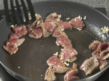 step3: 爆香蒜茸，牛肉炒至半熟，灒入酒。
Sauté minced garlic until fragrant and stir-fry beef till medium. Add in wine.