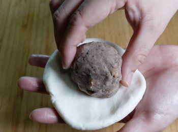 step5: 雙手沾油，拿一個麵團，滾圓，壓扁，把鹹味眉豆餡放中間，包起來，收口滾圓，再壓扁