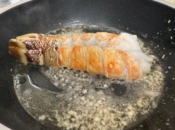 step1: 龍蝦解凍後，斬開一半，去殼只留尾巴殼，印乾水，灑上少少鹽和胡椒粉醃一陣。牛油起鑊，煎一煎龍蝦（半熟），中途加一茶匙蒜蓉，