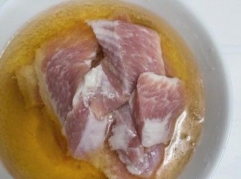 step1: 先將豬頸肉用清水略洗，廚房紙巾吸乾水份備用。豬頸肉建議薄切。然後倒入半罐啤酒浸泡時間30分鐘（需要放入雪櫃冷藏）