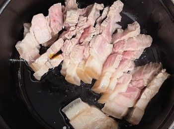 step4: 熱鍋倒入適量油；放入豬腩片略炒，倒入適量料理酒，炒一炒。