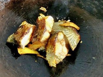 step8: 將魚尾用廚紙吸乾水份大火煎封 , 反轉煎加入薑片 2-3 片煎至熟透 , 再放入湯袋 .
