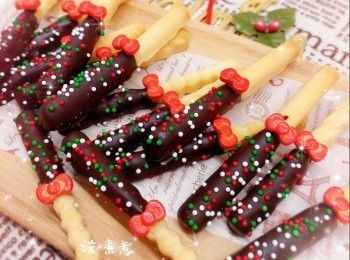 step10: <span class="group_2">朱古力醬裝飾</span>： 1. 將黑／白朱古力用熱水坐溶（亦可用微波爐加熱1.5分鐘成朱古力醬；朱古力加熱不可超過50°，否則會變質而失去光澤） 2. 將曲奇棒沾上適量的朱古力醬，然後放上聖誕裝飾糖，再灑上適量的彩色糖珠，待朱古力完全凝固，即可