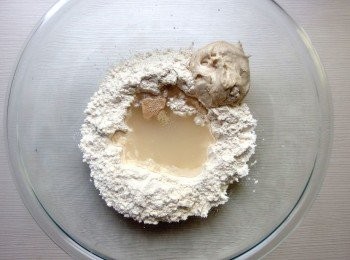 step2: 將中筋麵粉放入調理碗裡,在麵粉中間倒入水,加入酵母粉靜置5分鐘,放入發酵種及黑糖,用擀麵棍稍加混合,最後加入沙拉油後將麵粉混合成糰狀。將麵糰移至工作檯面,灑上些許手粉,將麵糰揉製約7-8分鐘,搓揉成光滑狀的麵糰即可。