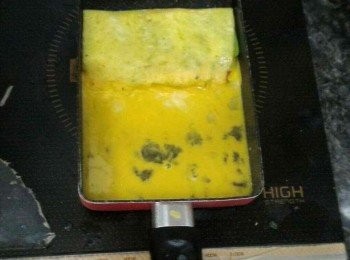 step8: 將半好的奄列向上推，煎pan下半部倒入剩下的蛋汁，用木剷稍微牽起一點奄列讓蛋汁黏住奄列邊緣。