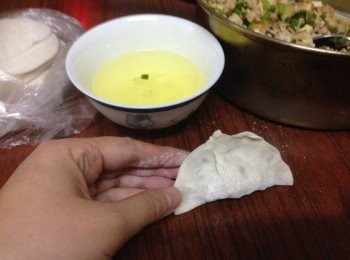 step3: 用匙一羹餡料成鳯眼型在麵皮中心後連餡在內對摺成半圎，用一對手的母指及食指及虎口位左右兩邊握實餃子邊向中心推成花邊揑實便可