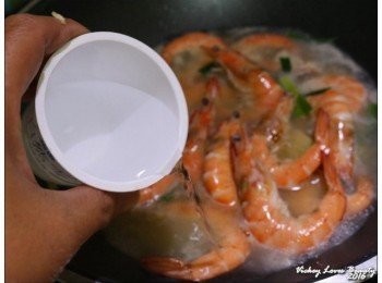 step4: 接著再倒入一米量杯的米酒拌匀，翻拌大約３０秒至蝦子變色後撈起備用