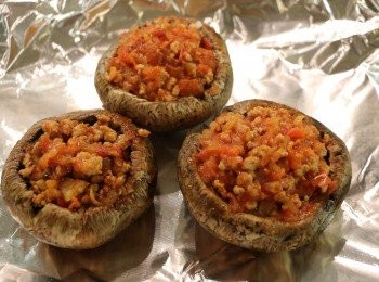 step6: 將炒好的番茄肉醬餡填入蘑菇傘內。烤盤鋪上鋁箔紙，噴上少許油，把填滿的蘑菇放上，然後放入已預熱的烤箱180度先烤15分鐘至蘑菇半軟化。