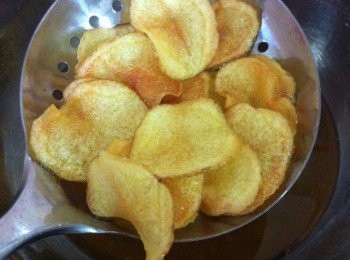 step2: 取出鍋加入適量的炸油，以低溫把炸油弄熱，然後加入處理好的馬鈴薯片，一片一片的下鍋油炸，油炸的過程不可以偷懶哦~以最低火慢慢油炸，不時要以木筷子翻轉薯片。直到馬鈴薯變成金黃色鬆脆即可盛起，利用吸油紙吸乾油分，即可