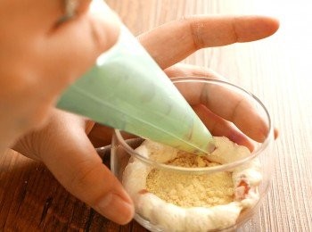 step6: 在甜品杯中，以唧袋由外到內唧入一圈忌廉，再鋪上一層曲奇碎，重覆至填滿，最後放上士多啤梨作裝飾即成。