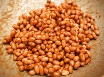 step4: 持續翻炒至鍋內的糖漿略微變深色並且開始有絲狀產生，這個時候用工具取出一顆花生丟入冷水中冷卻後吃吃看，如果花生沒有生味，且糖的口感是脆的就可以將花生取出倒入烤盤中。