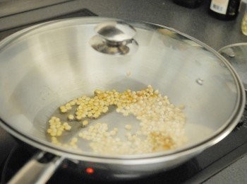 step2: 在大鑊/煲內下油，至油熱後（可放一粒粟米粒，如爆了即代表油夠熱）下粟米粒，拌勻