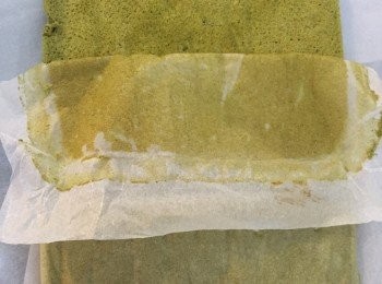 step8: 將牛油紙覆蓋在綠茶蛋糕的表面，然後將蛋糕反轉，輕輕撕走底部的牛油紙。