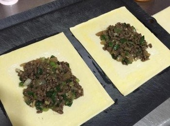 step2: 酥皮一張舖在放有烘焙紙的烤盤上，中間放入炒好的牛肉，邊邊留個1-2公分左右，邊緣接合處刷上蛋液