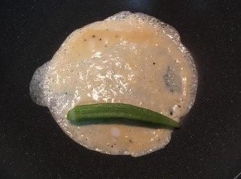 step6: 放入一根燙熟的秋葵，趁蛋液沒全熟時，慢慢捲起來。