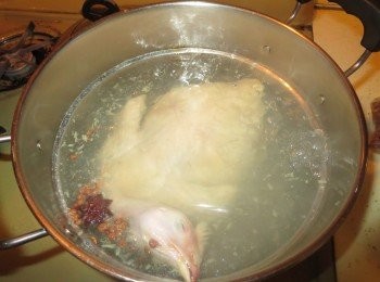 step2: 在汤锅里倒入可以没过三黄鸡的凉水，放入葱，姜，料酒，花椒和八角大火煮开后撇去浮沫，放入1茶匙半的盐，煮5分钟后，马上盖好锅盖，关掉火。