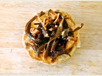 step3: 將全麥餐包剖半後，放入適量的紅椒麻辣黑菇醬，並淋上些許醬汁。