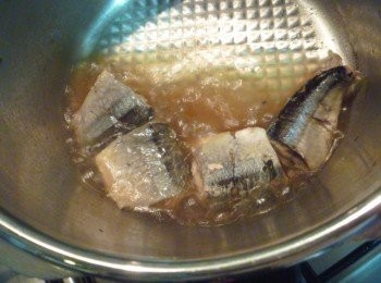 step4: 開鍋蓋,去除昆布乾,日本山椒及薑片,倒入醬油開中火將鍋子前傾偶爾翻秋刀魚(此時小心不要弄碎喔!)煮至收乾即可.