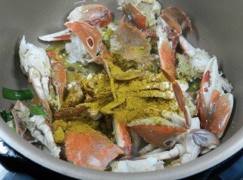 step6: 蟹肉變紅後開啟鍋蓋，先淋點米酒拌煮，再加入印度咖哩粉，直接開蓋在鍋內做拌煮，火力也可以維持，不會忽冷忽熱，更不用怕<span class="group_1">食材</span>煮焦