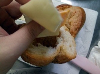 step7: 將法國香蒜麵包切開對半，挖掉部分麵包心，放進烤箱烤兩分鐘。烤好後加入乾酪片，